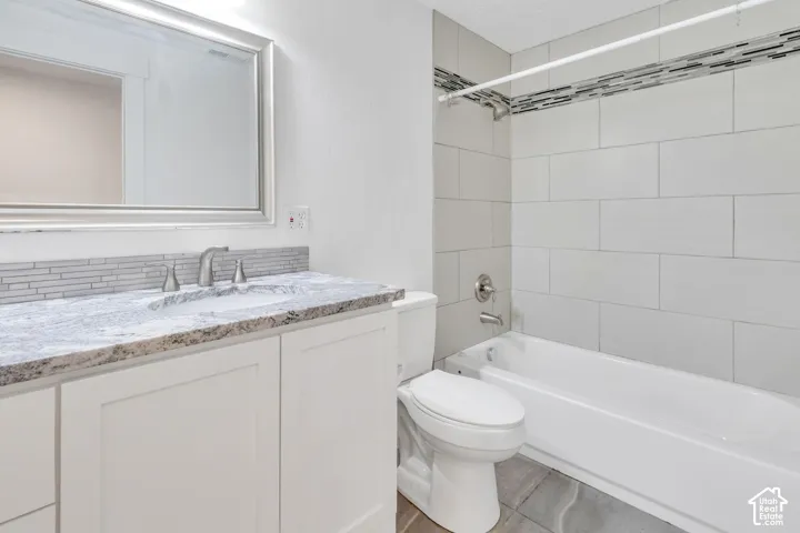 Vanity with stone countertop, tile backsplash, undermount sink, and brushed nickel fixtures
