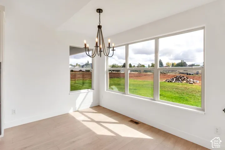 Open concept room featuring a multi-pane window, light wood-finish flooring, and a black wrought iron chandelier