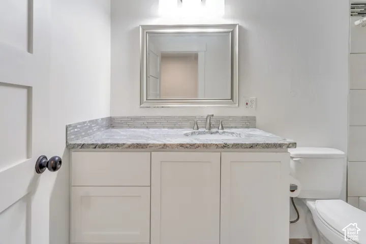 White shaker-style vanity with a light-toned countertop, mosaic tile backsplash, and a framed mirror