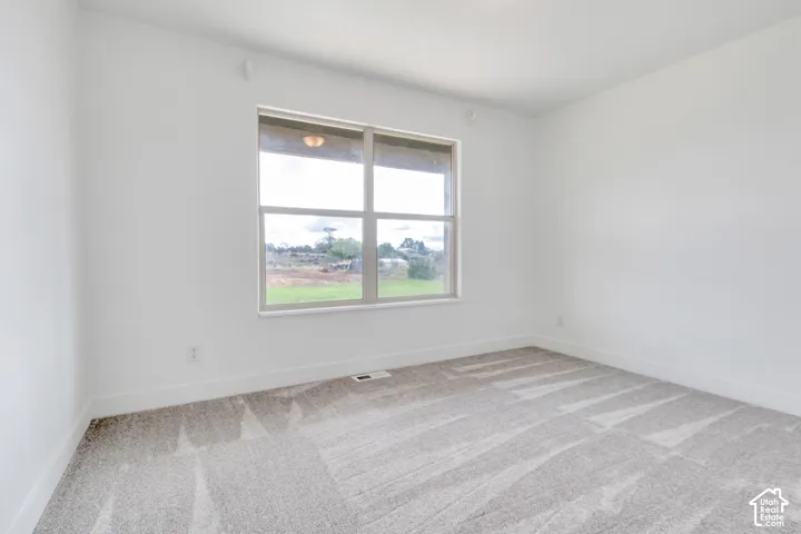 Neutral wall paint, window with white trim, and gray patterned carpeting
