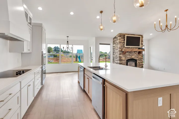 Open-concept kitchen featuring an oversized island with an integrated sink, stainless steel appliances, and wood-finish flooring