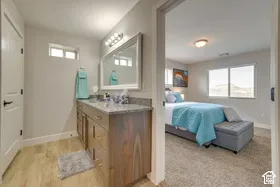 Bathroom featuring a single vanity with a granite-style countertop, wood-finish cabinetry, and a framed mirror