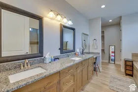 Dual vanity with granite countertops, wood-finish cabinetry, and undermount sinks
