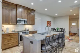 Kitchen featuring wood cabinetry, stainless steel appliances, a white subway tile backsplash, and an island with a countertop