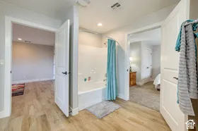 Bathroom with a built-in bathtub and shower combination, wood-finish flooring, and white paneled doors