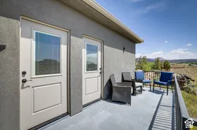 Exterior balcony featuring a solid railing, two glass-paneled doors, and a distant mountain backdrop