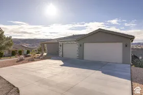 Concrete driveway leading to a multi-car garage with a stucco exterior and stone accent detailing