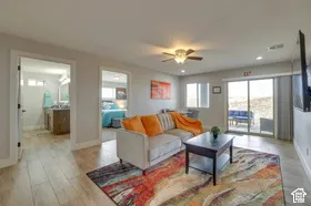 Wood-finish flooring throughout, featuring a ceiling fan with integrated lighting, recessed lighting, and sliding glass doors to the exterior