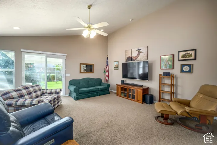 Vaulted ceiling with a ceiling fan, sliding glass door, carpeted flooring, and recessed lighting