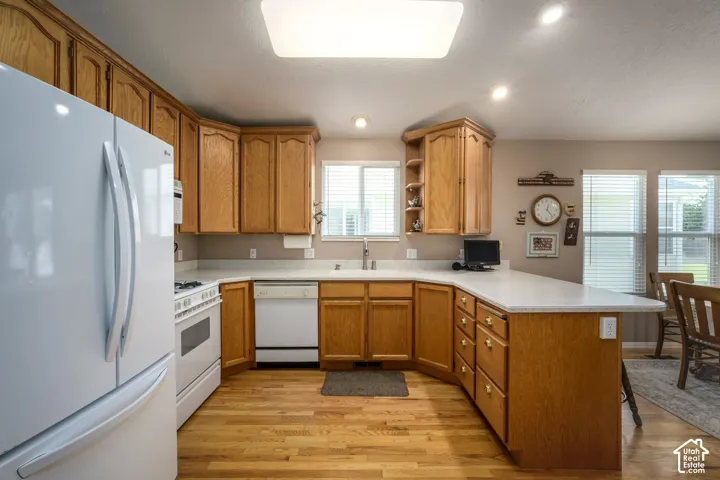 Kitchen featuring wood-finish cabinetry, solid surface countertops, a built-in dishwasher, and wood-finish flooring