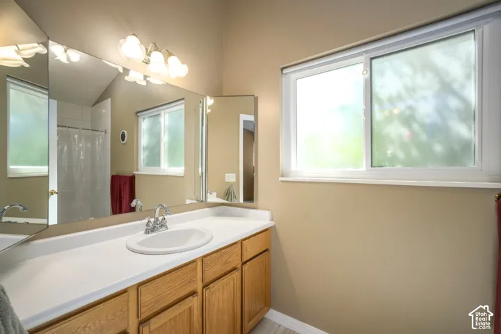 Vanity with integrated sink and chrome faucet, wood-finish cabinetry, and mirrored wall