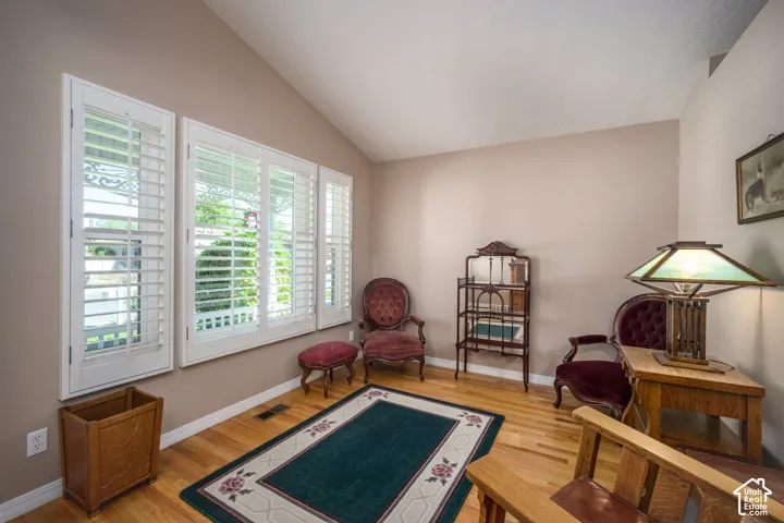 Vaulted ceiling, natural wood-finish flooring, plantation shutters, and neutral wall tones