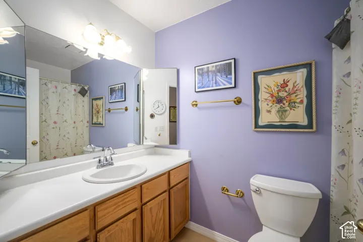 Vanity with a white countertop and wood-finish cabinetry, chrome faucet, and a large wall-mounted mirror
