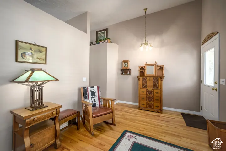 Hardwood flooring, neutral wall tones, decorative overhead lighting, and an entry door with a glass panel