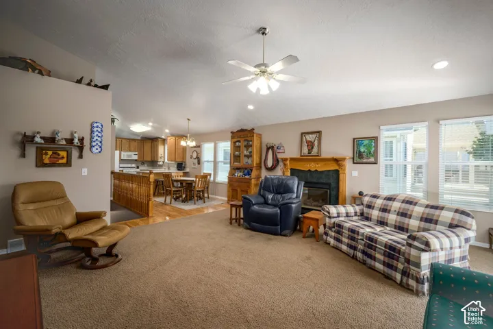 Living room featuring carpet flooring, fireplace with wood surround, and multiple windows