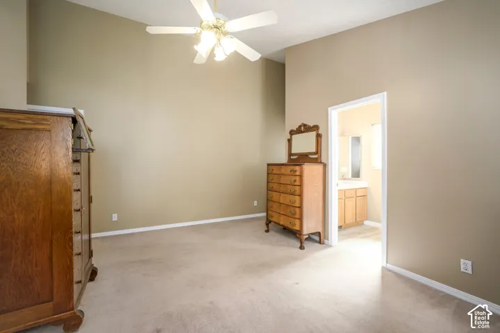 Carpeted room with vaulted ceilings and a ceiling fan with integrated lighting