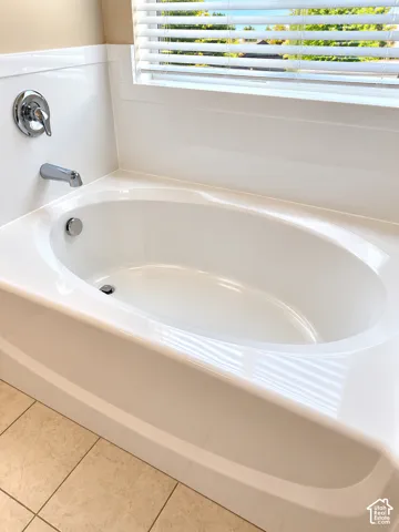 Built-in soaking tub with chrome fixtures and tiled flooring