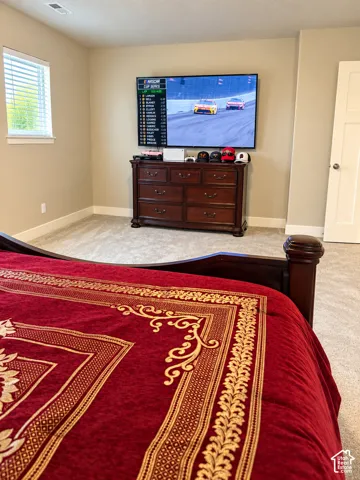Window with blinds, wall-mounted television, neutral wall color, light-colored carpet, white trim