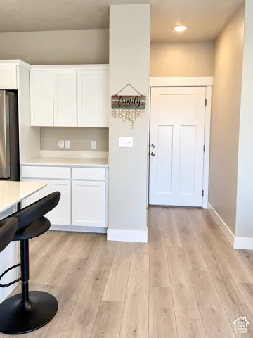 White shaker cabinetry with brushed nickel hardware, light-toned countertops, and wood-finish flooring