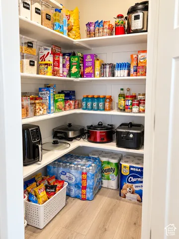 Built-in shelving with L-shaped configuration, paneled walls, wood-finish flooring, and ample storage space