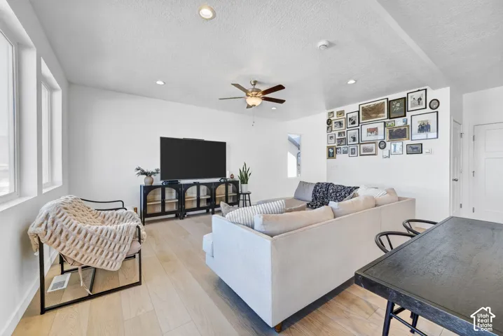 Spacious living area featuring large windows, wood-finish flooring, recessed lighting, and a ceiling fan