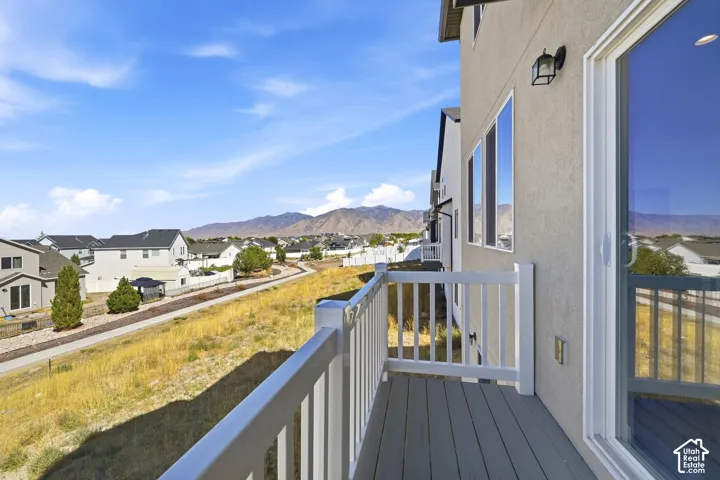 Balcony with composite decking and white railing, sliding glass door, and exterior wall sconce