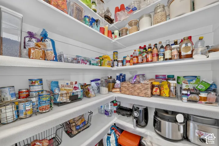 Pantry with Built-in white shelving providing extensive storage, corner configuration maximizing space, and multiple tiers for organization