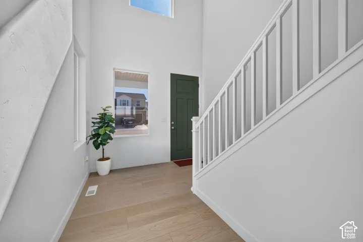 Two-story entry with wood-finish flooring, a contemporary staircase, and a dark green entry door