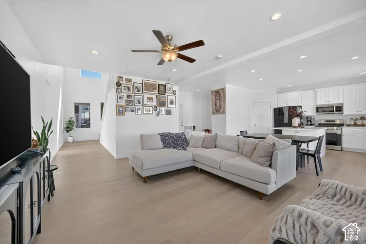 Expansive open-concept living area with light wood-finish flooring, recessed lighting, and a ceiling fan
