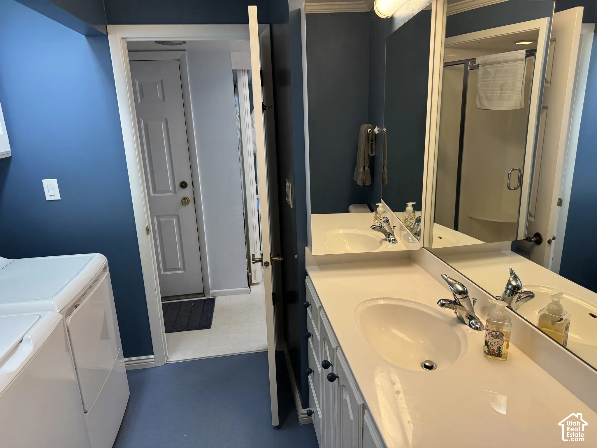 Dual vanity with integrated sinks and chrome fixtures, framed mirror, and a shower enclosure with a glass door