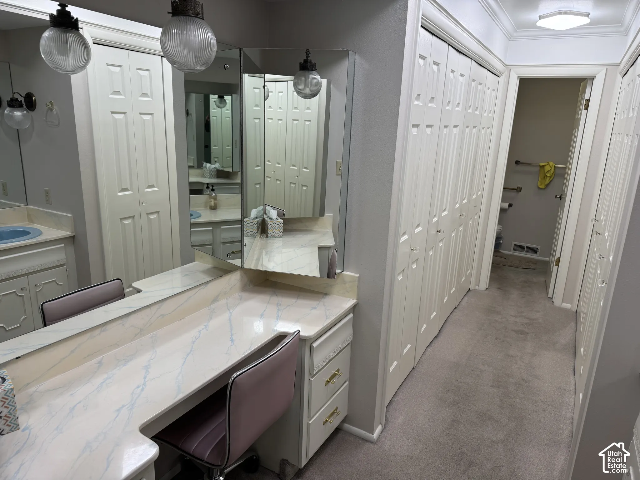Built-in vanity with integrated mirrors, multiple storage closets, and wall-mounted light fixtures