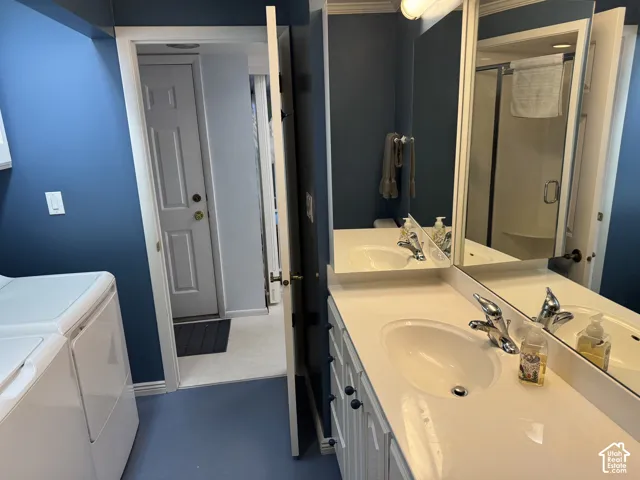 Dual vanity with integrated sinks and chrome fixtures, framed mirror, and a shower enclosure with a glass door