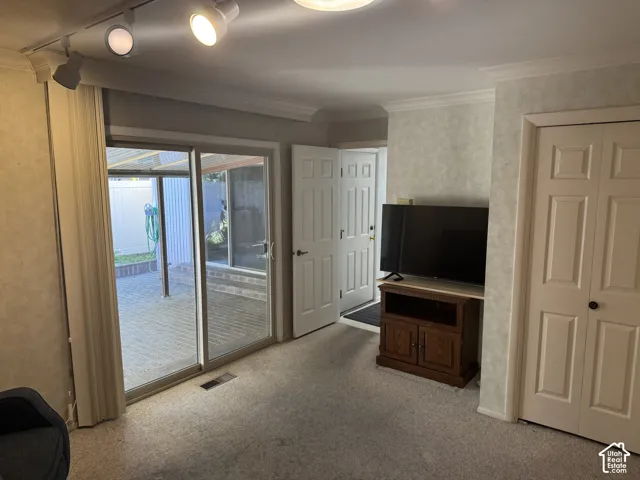 Sliding glass door, track lighting, crown molding, built-in closet, patio with paver flooring