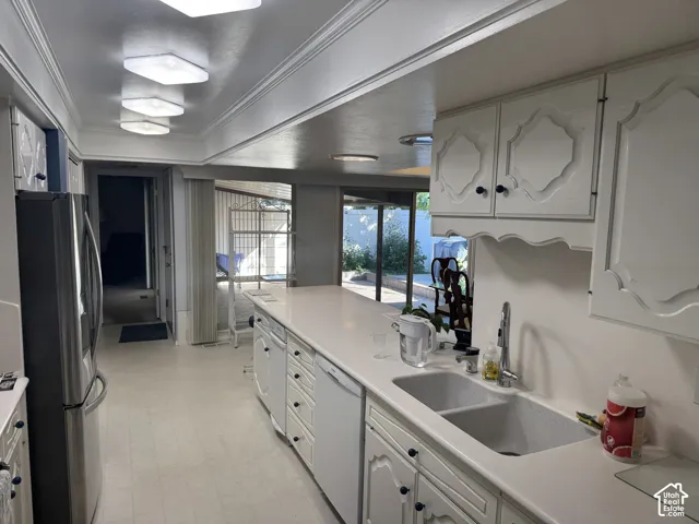 Kitchen featuring white cabinetry with dark hardware, white countertops, a double basin sink with a high-arc faucet, and stainless steel appliances
