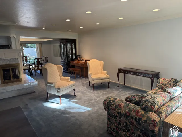 Recessed ceiling lighting, crown molding, fireplace with stone surround, and an open archway