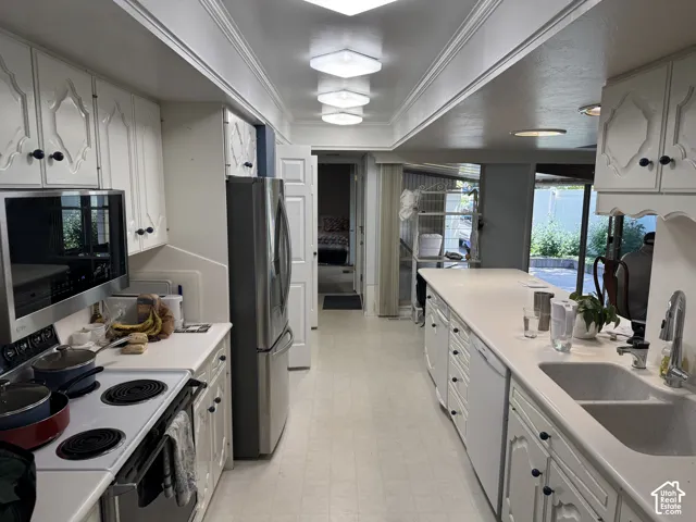 White cabinetry with decorative accents, stainless steel refrigerator, white countertops, built-in microwave, and a dual basin sink