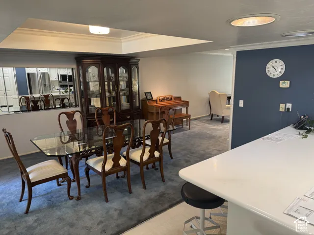 Recessed ceiling lighting, tray ceiling detail, mirrored wall accent, and a built-in breakfast bar