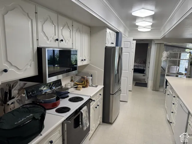 White cabinetry with decorative routed panels, stainless steel over-the-range microwave, stainless steel side-by-side refrigerator, and flush-mount ceiling lighting