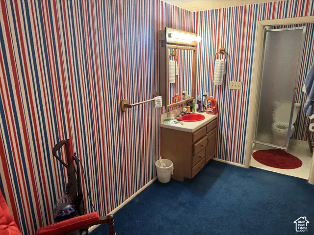 Wood-finish vanity with a red vessel sink and a wall-mounted mirror