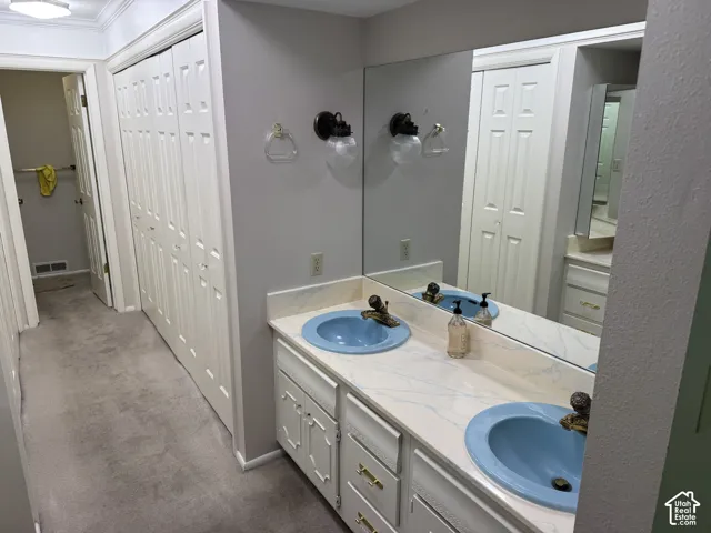 Dual vanity with light blue basin sinks, white cabinetry, and wall-mounted sconce lighting