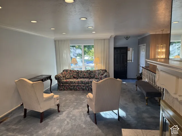 Recessed ceiling lighting, crown molding, double pane windows, dark-stained entry door, and a white wood fireplace mantel with a marble surround