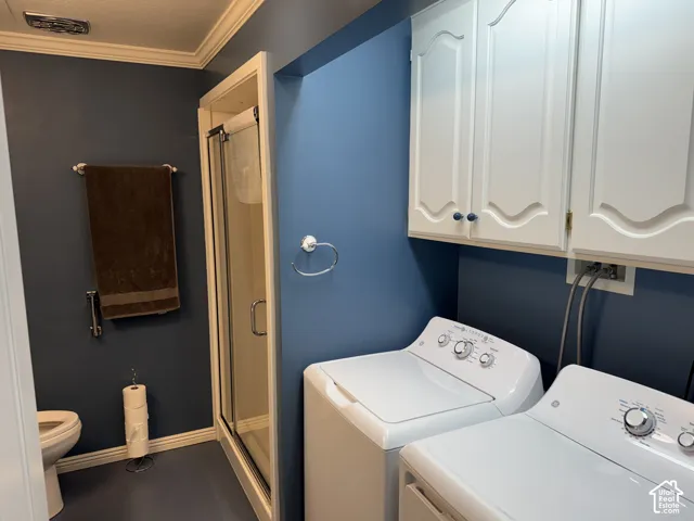 White cabinetry with sculpted details, crown molding, a shower enclosure with a clear glass door, and a toilet
