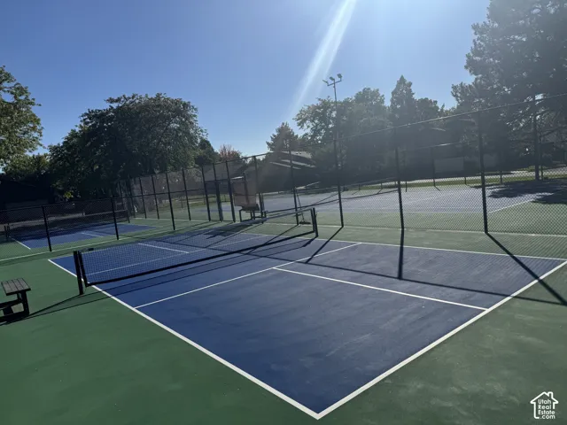 Multiple outdoor courts with green and blue surfaces, equipped with netting and perimeter fencing
