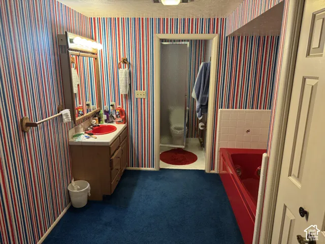 Bathroom featuring a built-in vanity, red basin sink, mirrored medicine cabinet, and a red bathtub