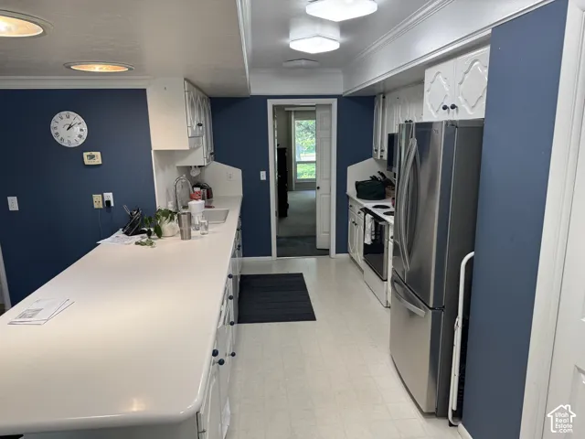 Kitchen featuring white cabinetry, light-toned countertops, and a stainless steel refrigerator