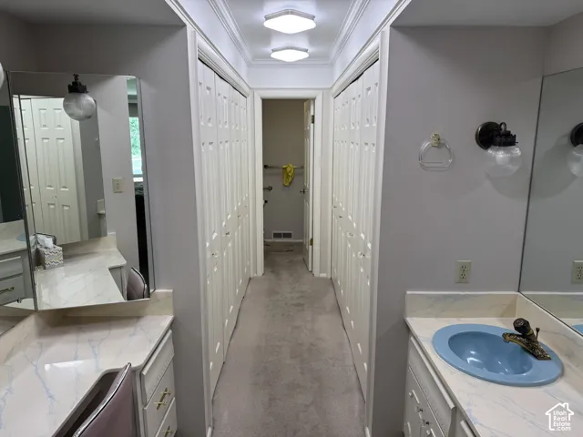 Corridor featuring a vanity area with a built-in mirror, dual closet doors, and recessed ceiling lighting