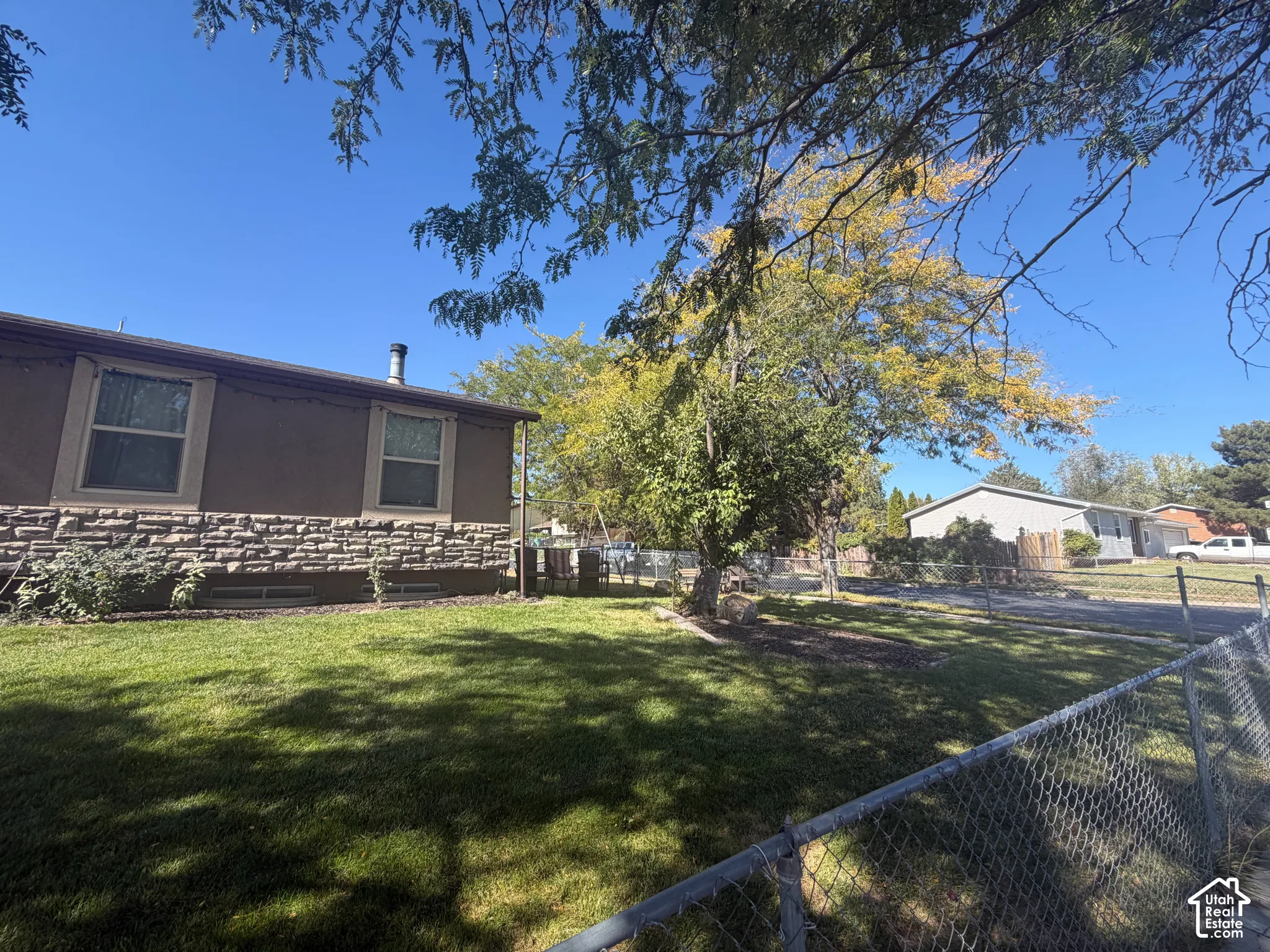 Chain link fence enclosing a grass yard with mature trees