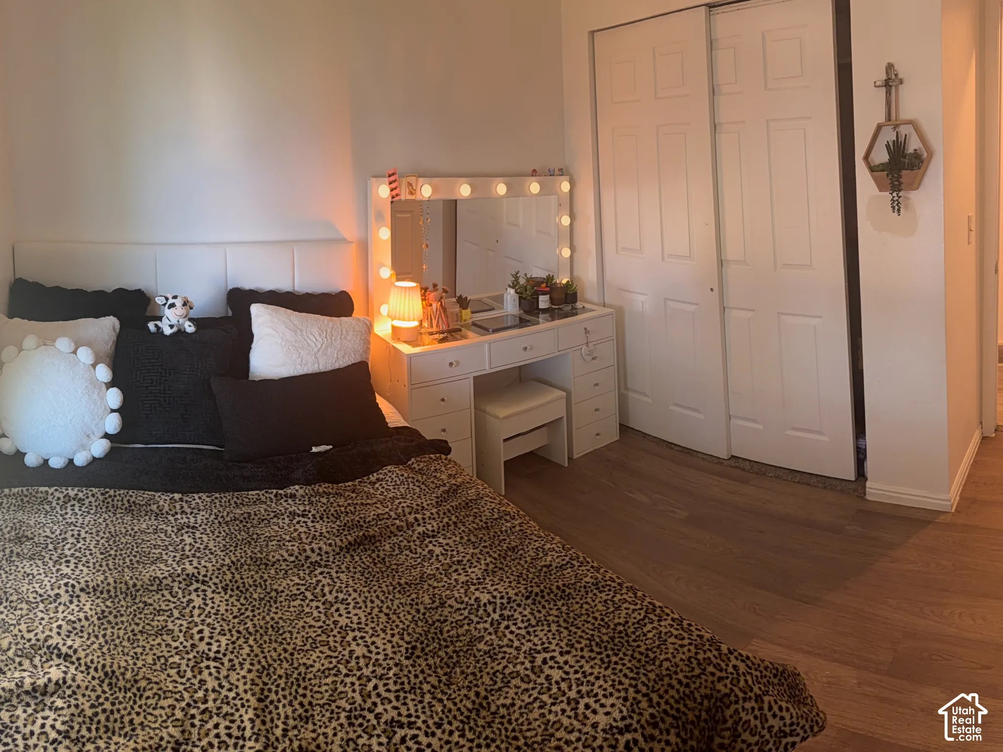 Light wood-finish flooring, white walls, and a window with a dark roller shade