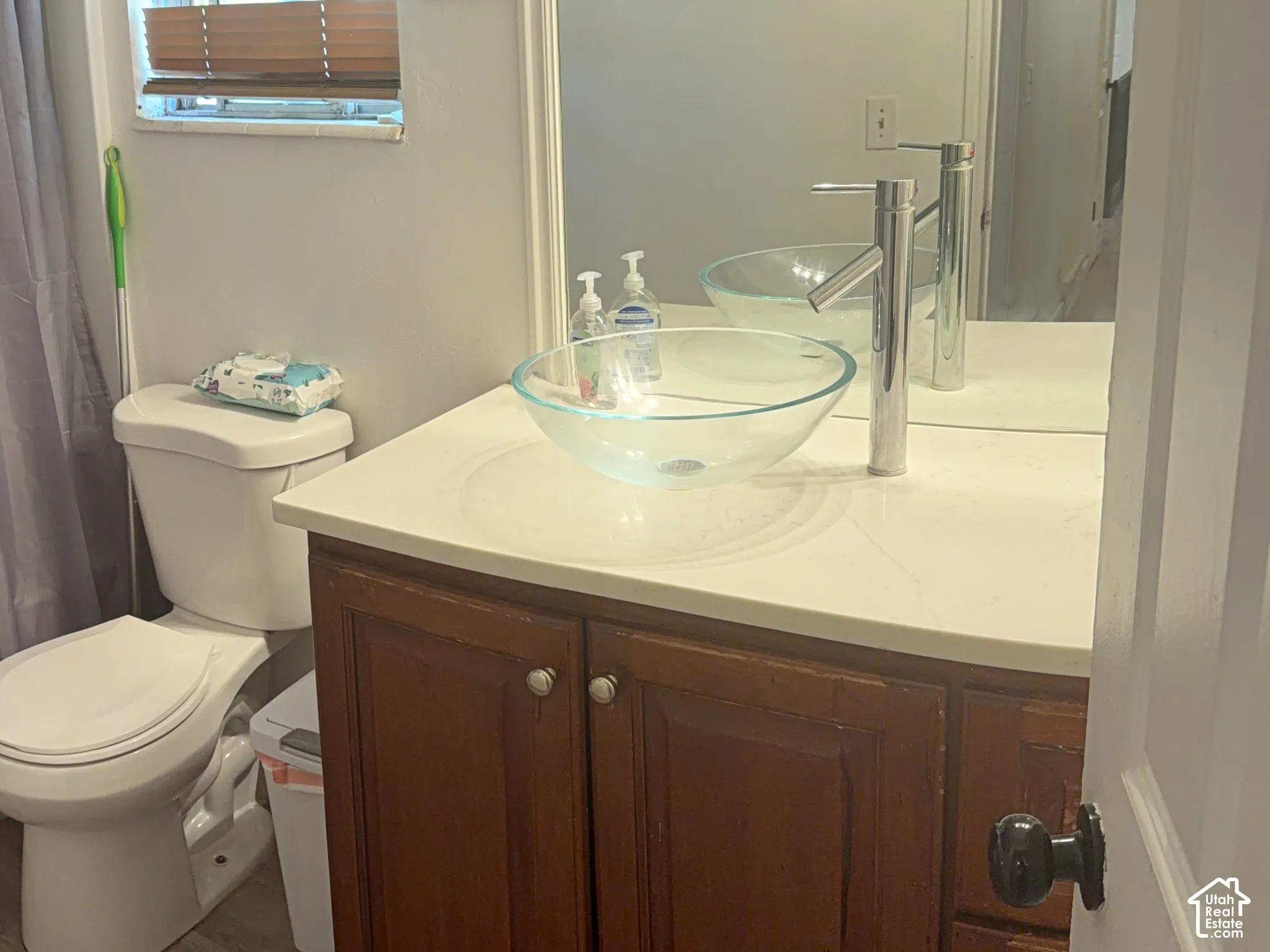 Modern vessel sink with a chrome faucet, wood-finish vanity, and light-toned countertop