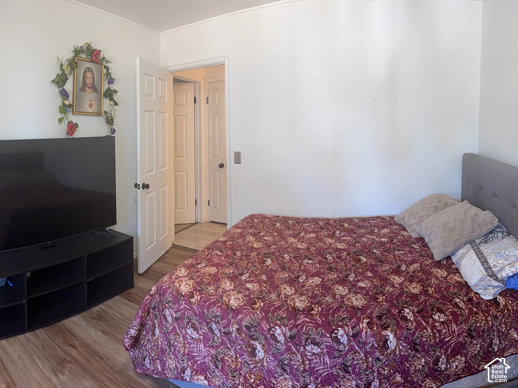 Wood-finish flooring with white walls and a paneled interior door